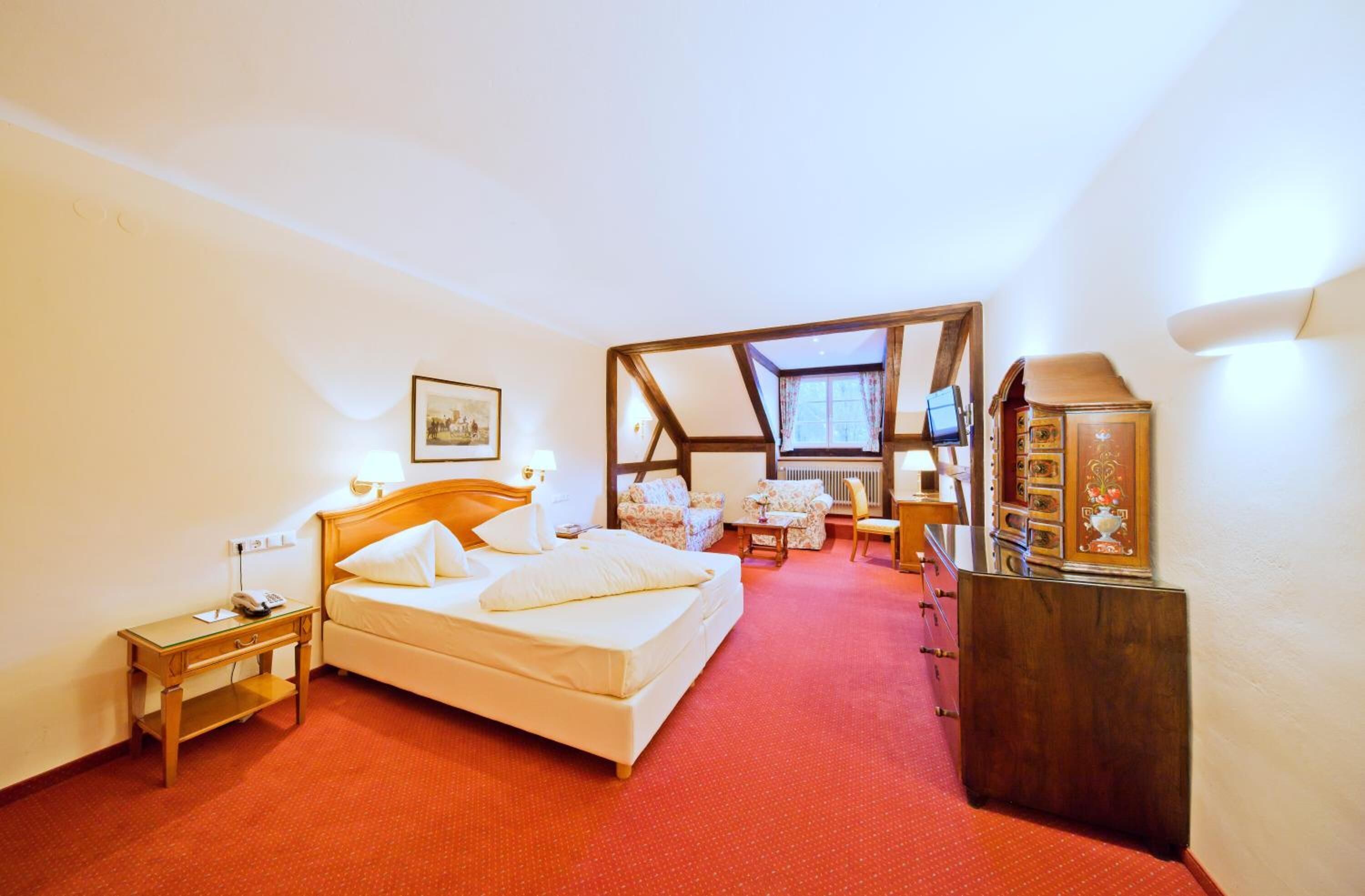 Een slaapkamer met een bed, nachtkastje, lamp en een houten kast.