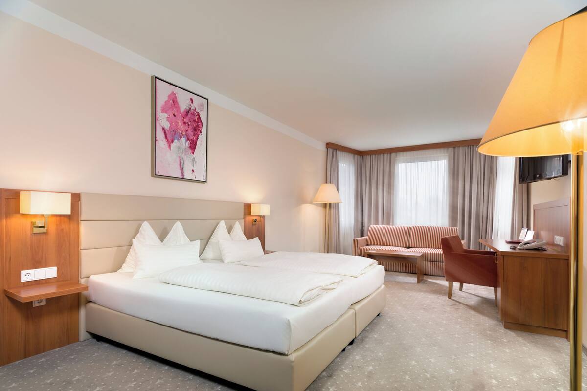 Una habitación de hotel con una cama grande, un sofá, un escritorio y una televisión.