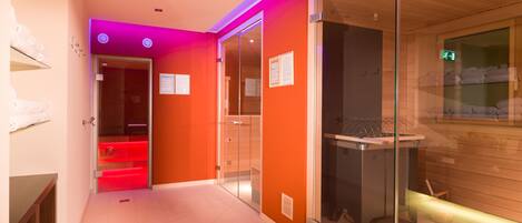 Un moderno vestíbulo de hotel con un panel de vidrio, un mostrador de recepción y una sauna visibles a través del cristal.