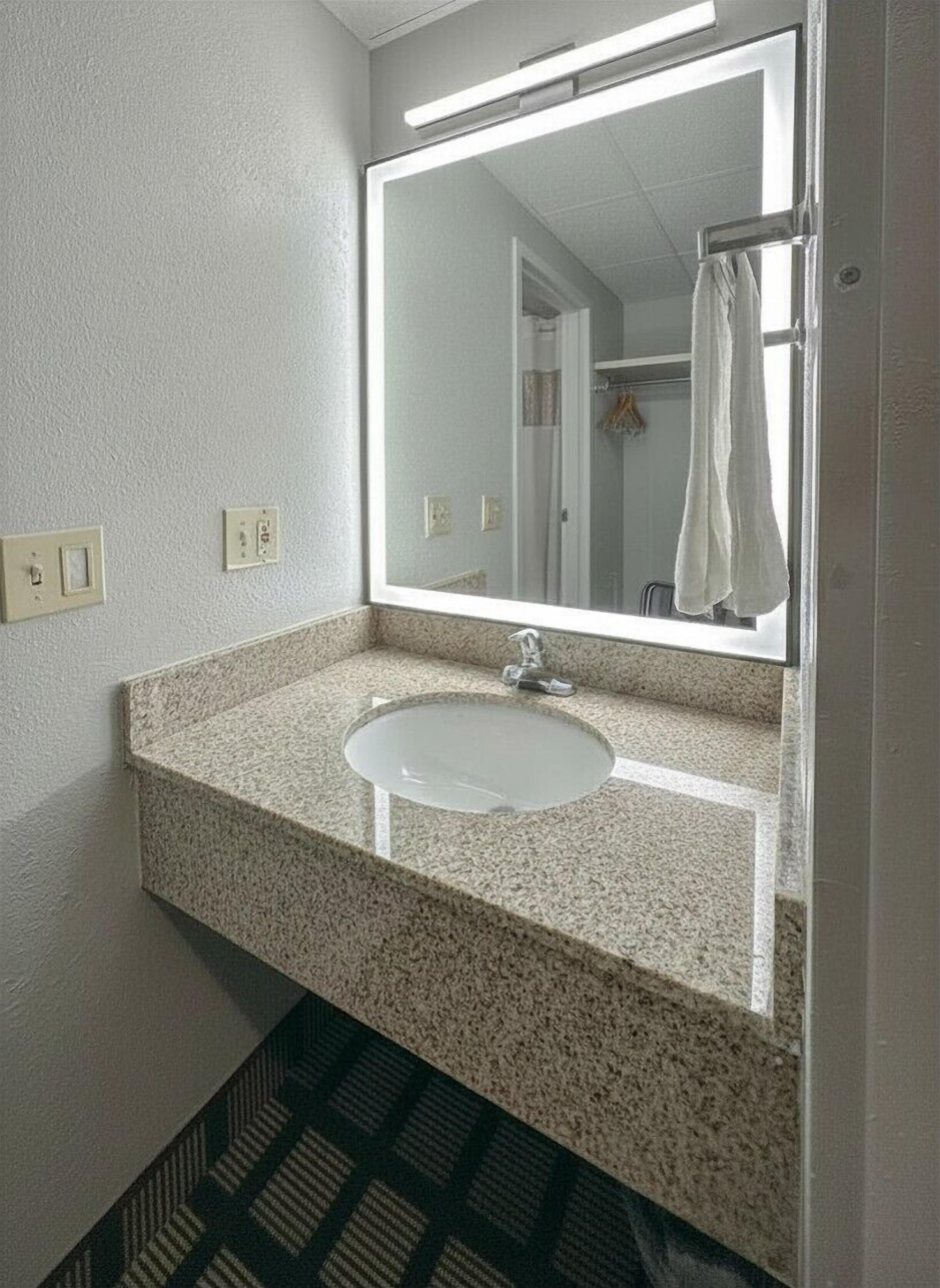 A bathroom with a granite countertop sink, a mirror, and a shower curtain.
