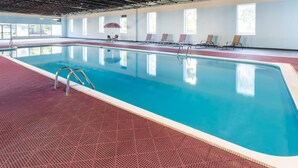 Una piscina interior con agua cristalina, suelo de seguridad rojo y sillas de descanso a lo largo de la pared.