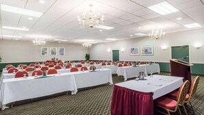 Un salón de conferencias con filas de mesas, sillas y un atril.