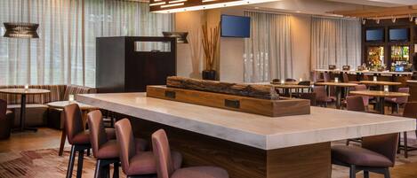 A modern bar area with a central island, bar stools, and a flat-screen TV mounted on the wall.