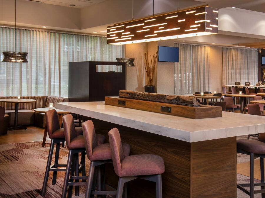A modern bar area with a central island, bar stools, and a flat-screen TV mounted on the wall.
