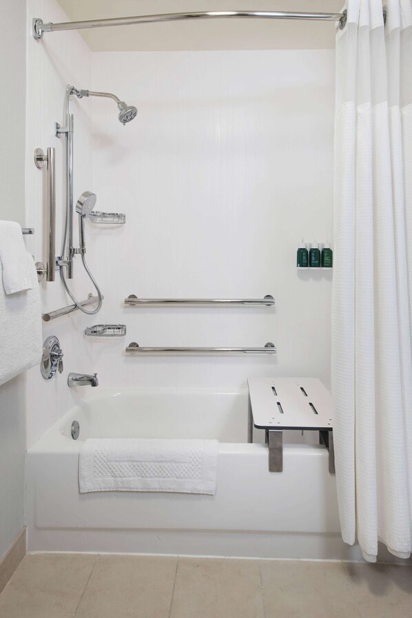 A modern bathroom with a walk-in shower, grab bars, a bathtub, and a towel rack.