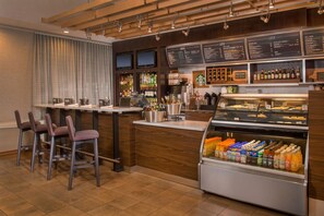 A bar area with seating, a beverage display, and a menu board.