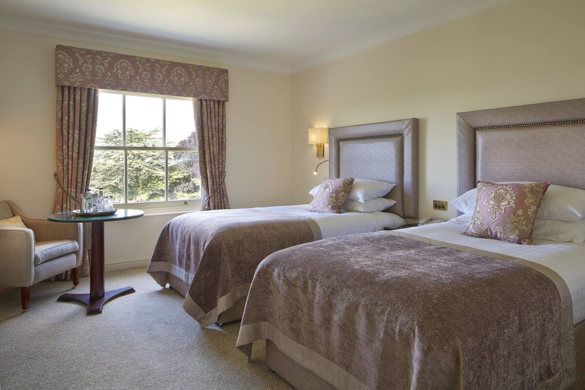 Une chambre d’hôtel avec deux lits, une petite table et une chaise.