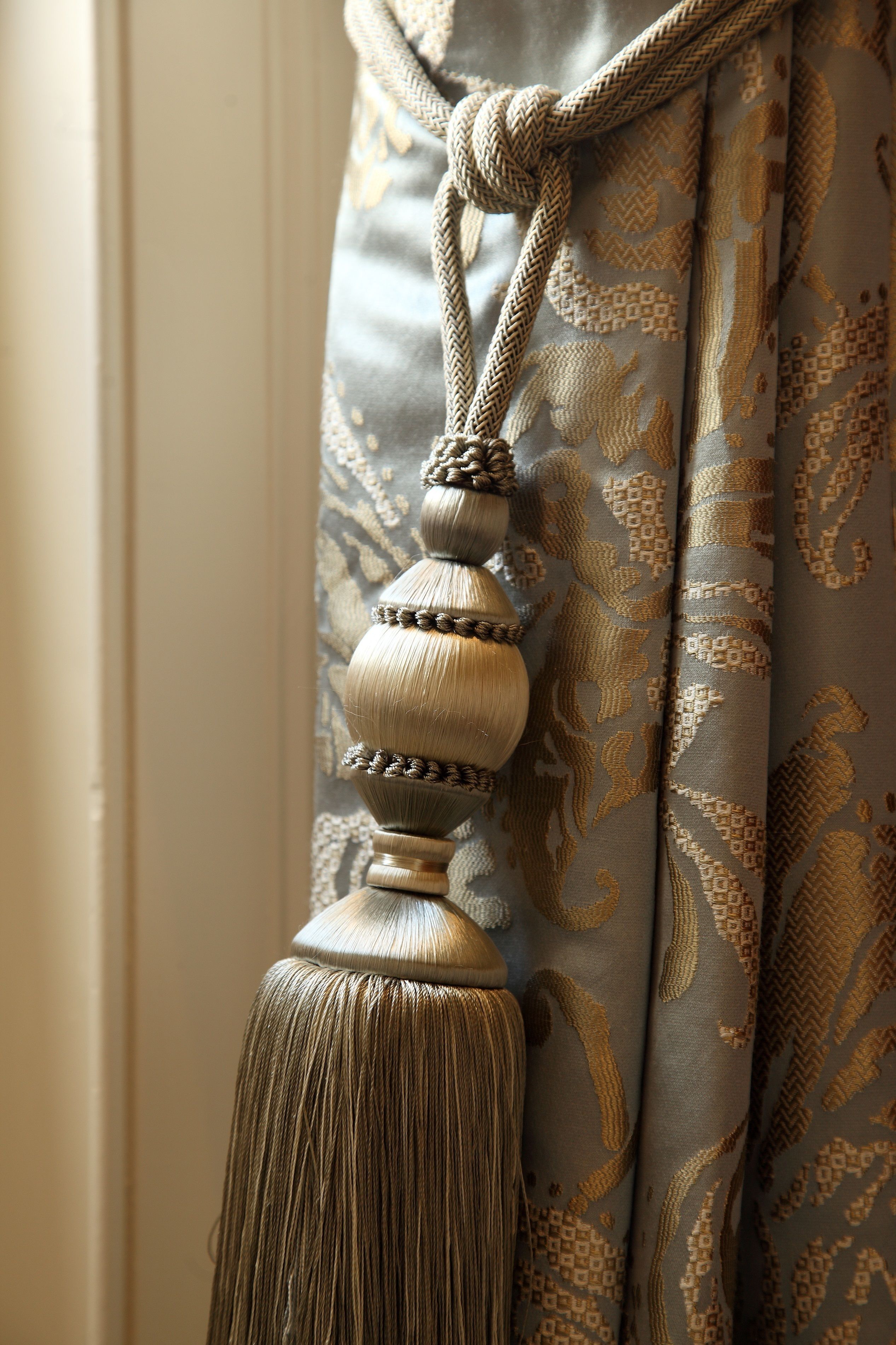 A close-up of a curtain with a tassel and a decorative knot.
