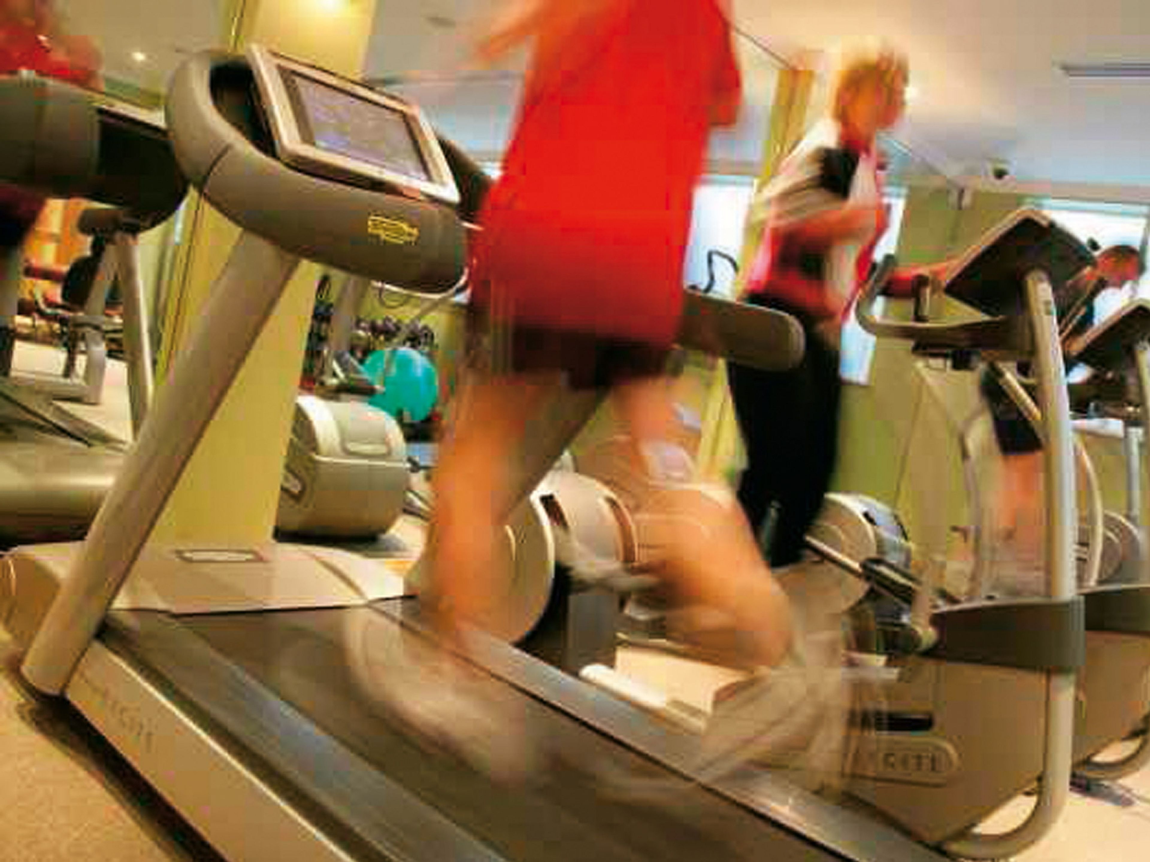 Una cinta de correr en un gimnasio, con una pantalla digital y un espejo.