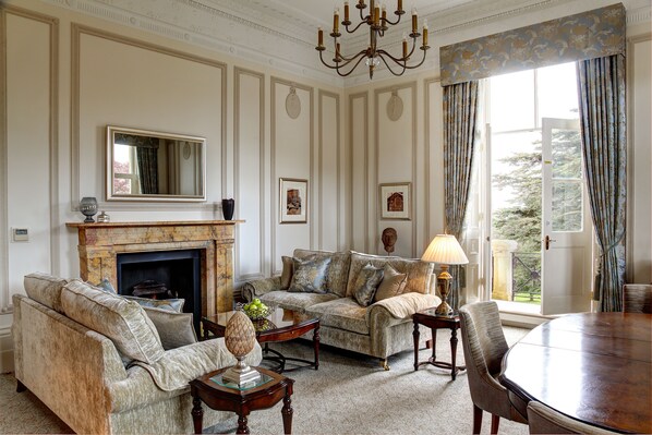 A traditional living room with a fireplace, two sofas, a coffee table, and a dining table. - Macdonald Bath Spa (Bath)