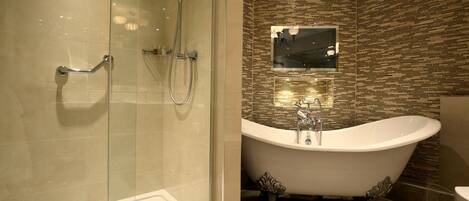 Un baño moderno con ducha envuelta en vidrio, una bañera independiente y un espejo montado en la pared.
