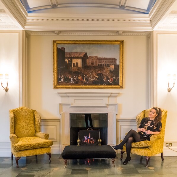 A room with a fireplace, two armchairs, and a large painting above it. - Macdonald Bath Spa (Bath)