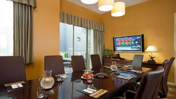 A conference room with a long table, chairs, a television, and a lamp.