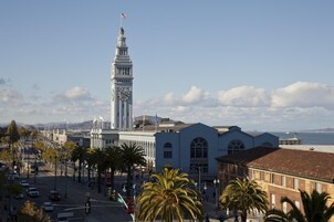 A coastal cityscape with a prominent clock tower, palm trees lining the streets, and a view of the ocean.