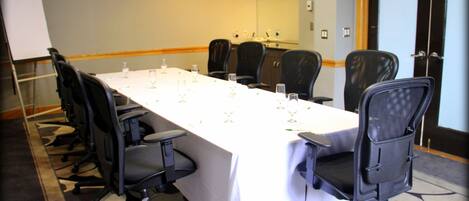 A conference room with a long table, multiple chairs, and a whiteboard.