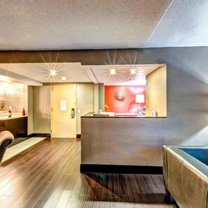 A reception area with a desk, chairs, and a wall-mounted lamp. - Holiday Inn Princeton by IHG (Princeton)