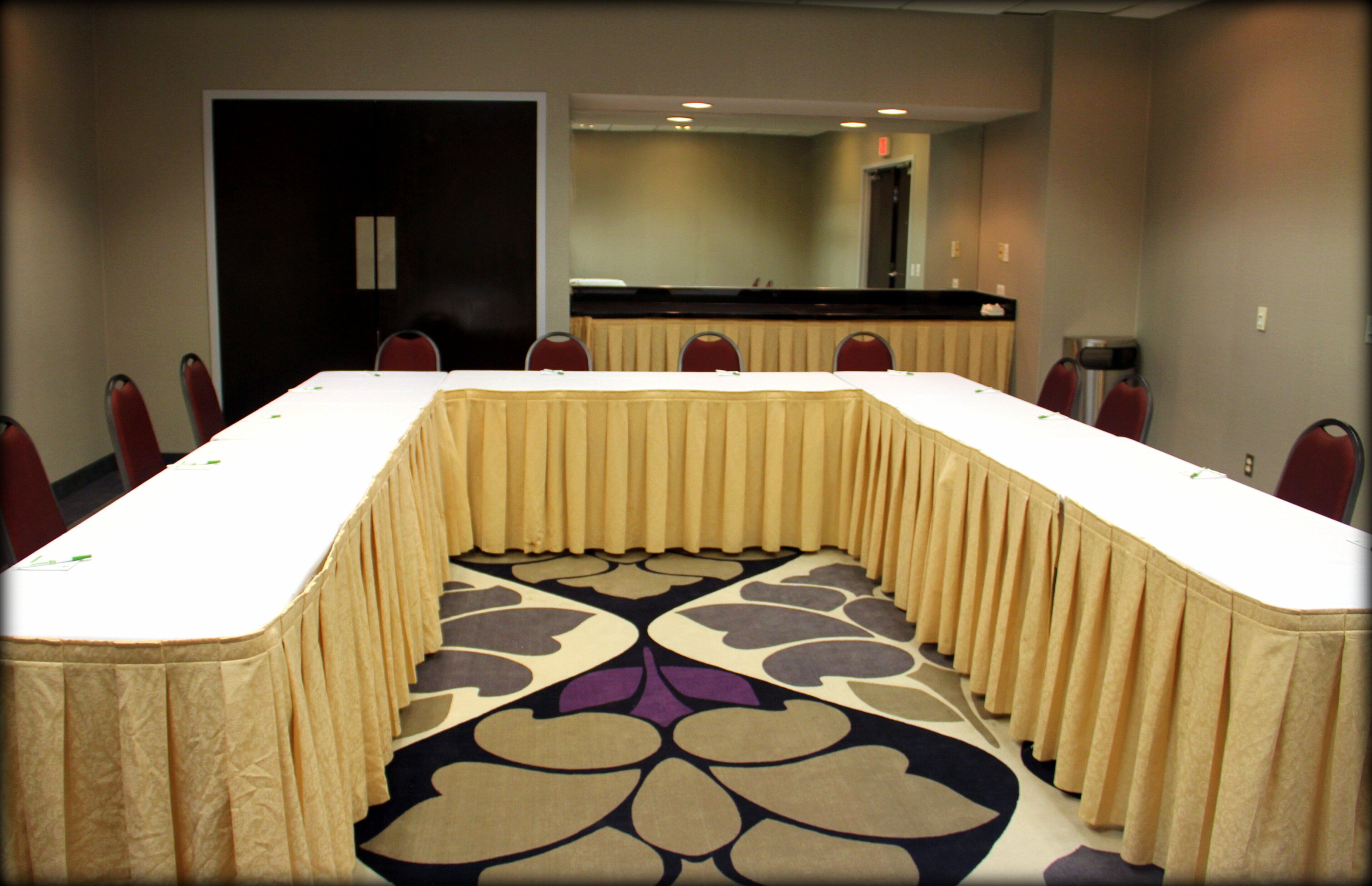 A conference room with a long table, chairs, and a patterned carpet.
