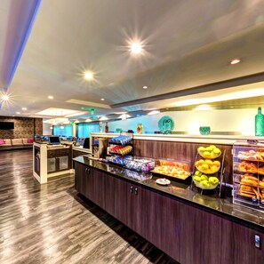 A buffet area with various food options, a seating area with a sofa, and a television screen. - Holiday Inn Princeton by IHG (Princeton)