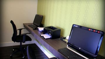 Un escritorio con una computadora portátil, una impresora y una silla.