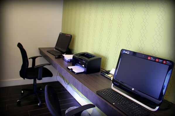 A desk with a laptop, a printer, and a chair.