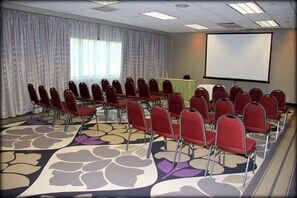 A conference room with rows of red chairs, a projector screen, and a table with a green tablecloth. - Holiday Inn Princeton by IHG (Princeton)