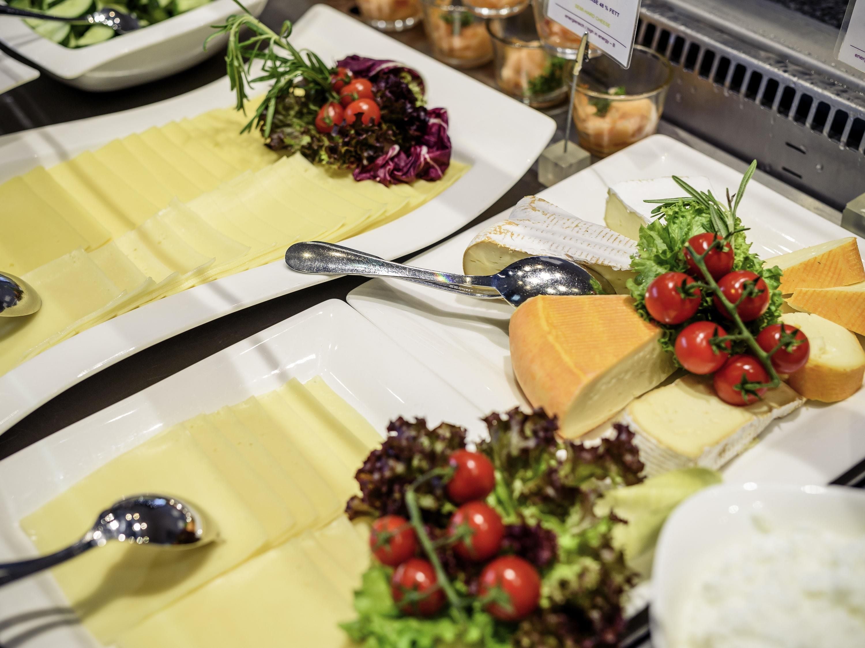 A buffet with various food items including cheese, salad, and a spoon.