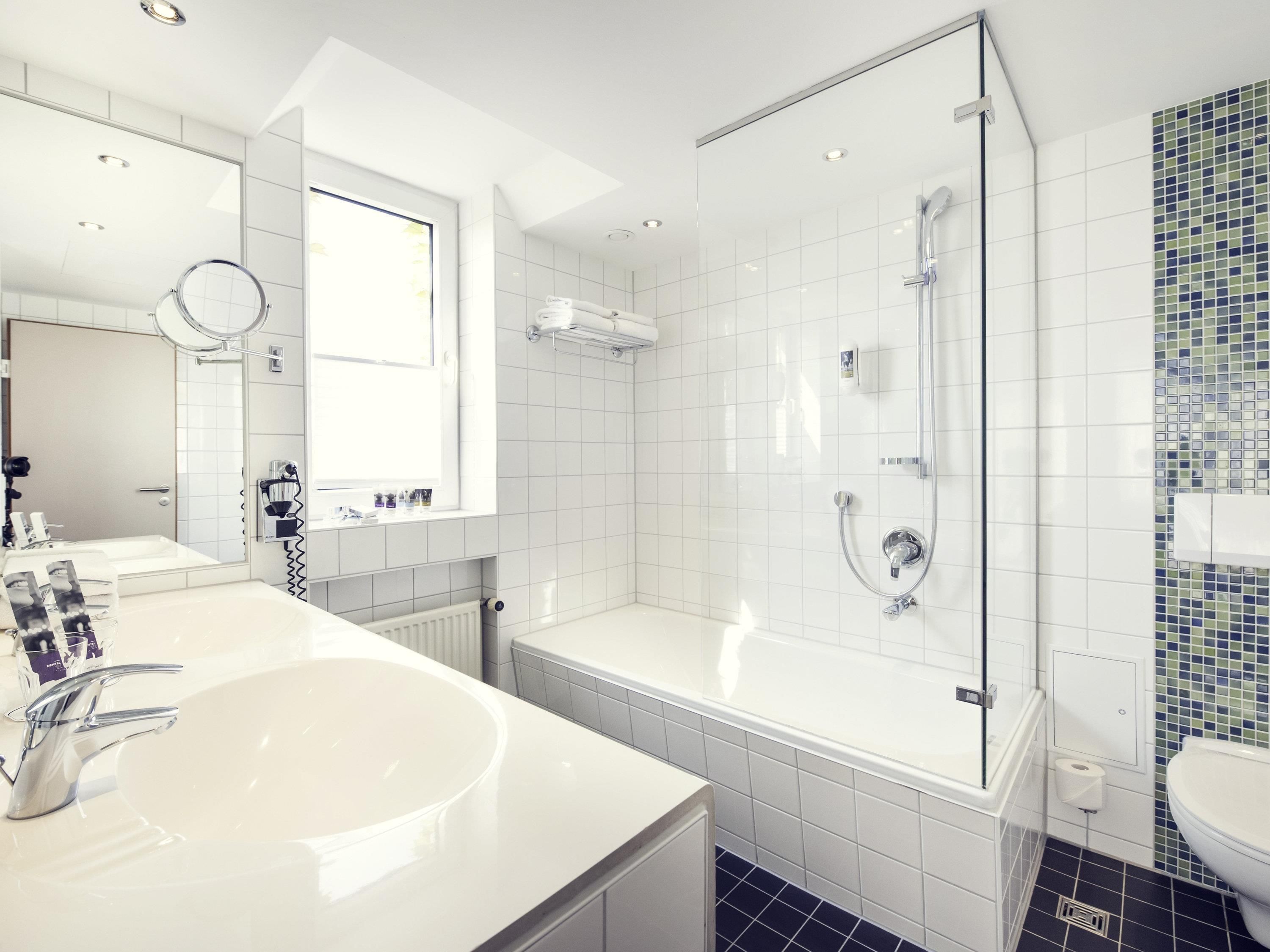 Ein modernes Badezimmer mit einem großen weißen Waschbecken, einer Badewanne, einer Dusche und einem WC.