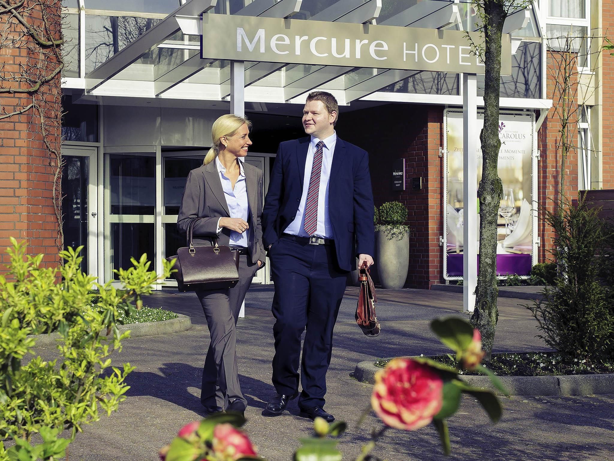 A man and a woman walking towards the Mercure Hotel entrance.