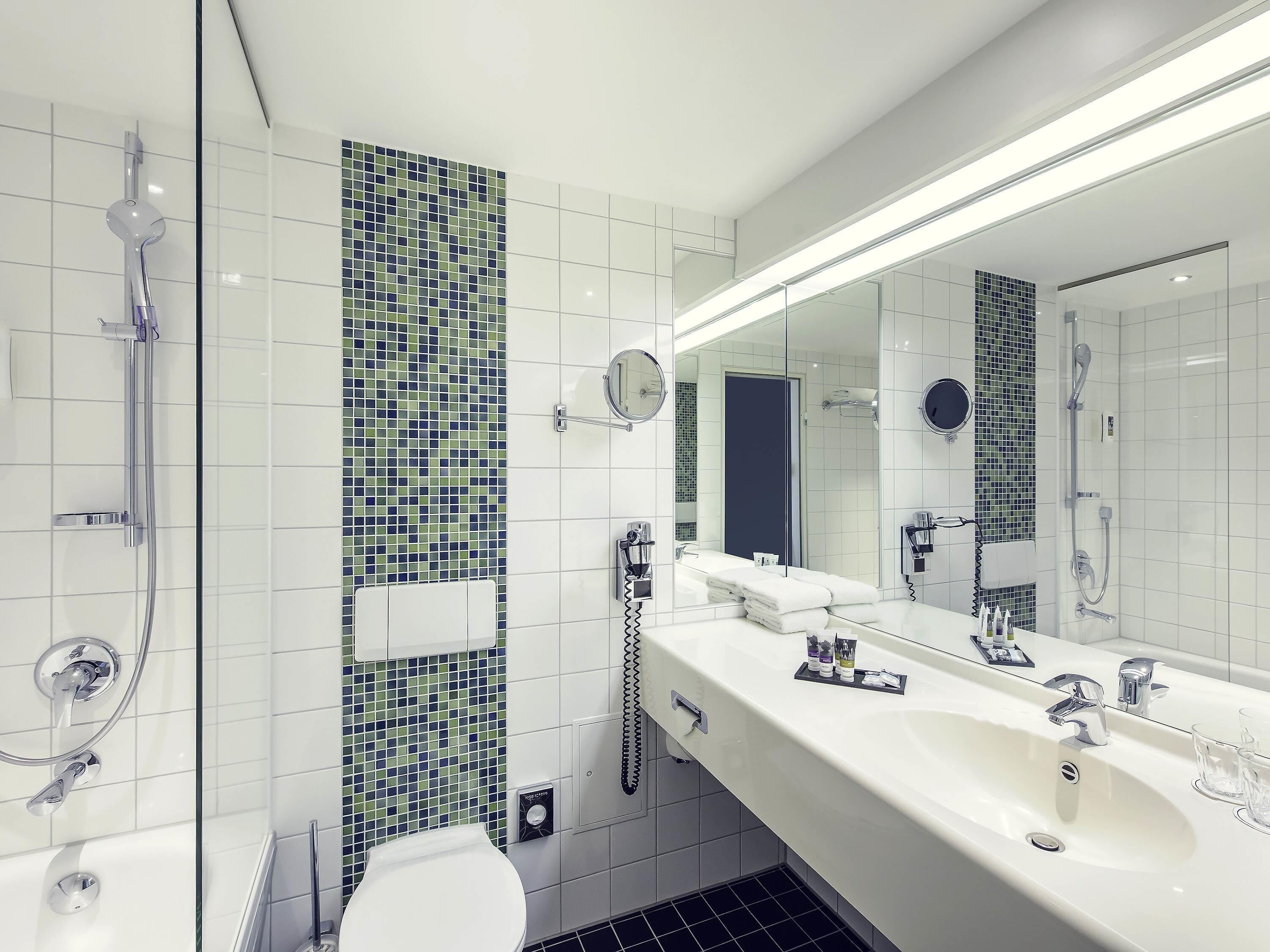 Une salle de bain moderne équipée d’une douche, de toilettes et d’un grand miroir.