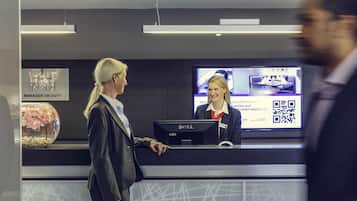Ein Hotelrezeptionstresen mit einem digitalen Bildschirm, der Zimmeroptionen und einen QR-Code anzeigt.