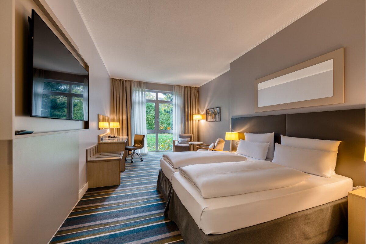 Une chambre d’hôtel avec un grand lit, deux tables de chevet, un bureau, une chaise et un téléviseur.