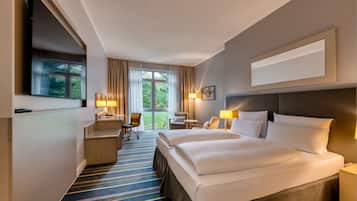 A hotel room with a large bed, two bedside tables, a desk, a chair, and a TV.