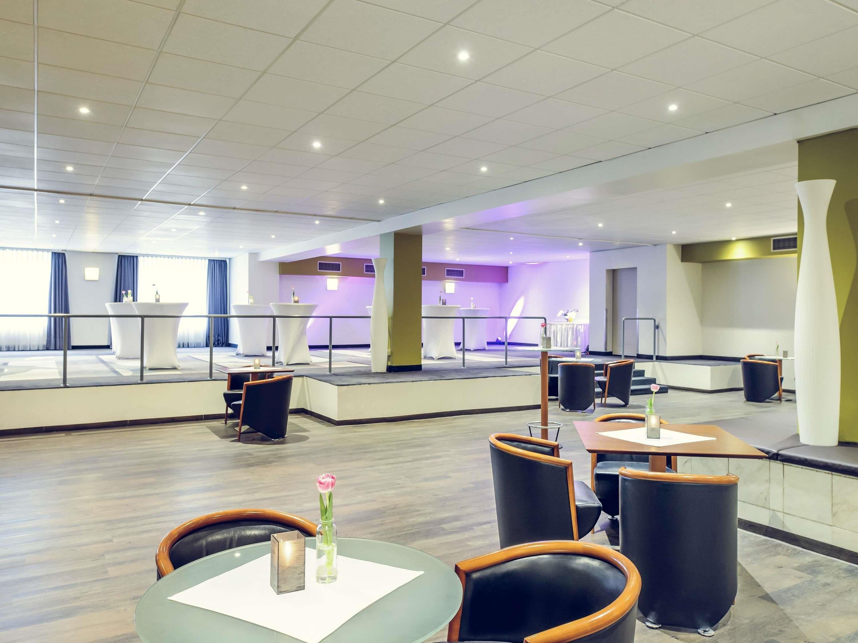 A spacious hotel lobby with a reception desk, seating area, and a view of the pool.