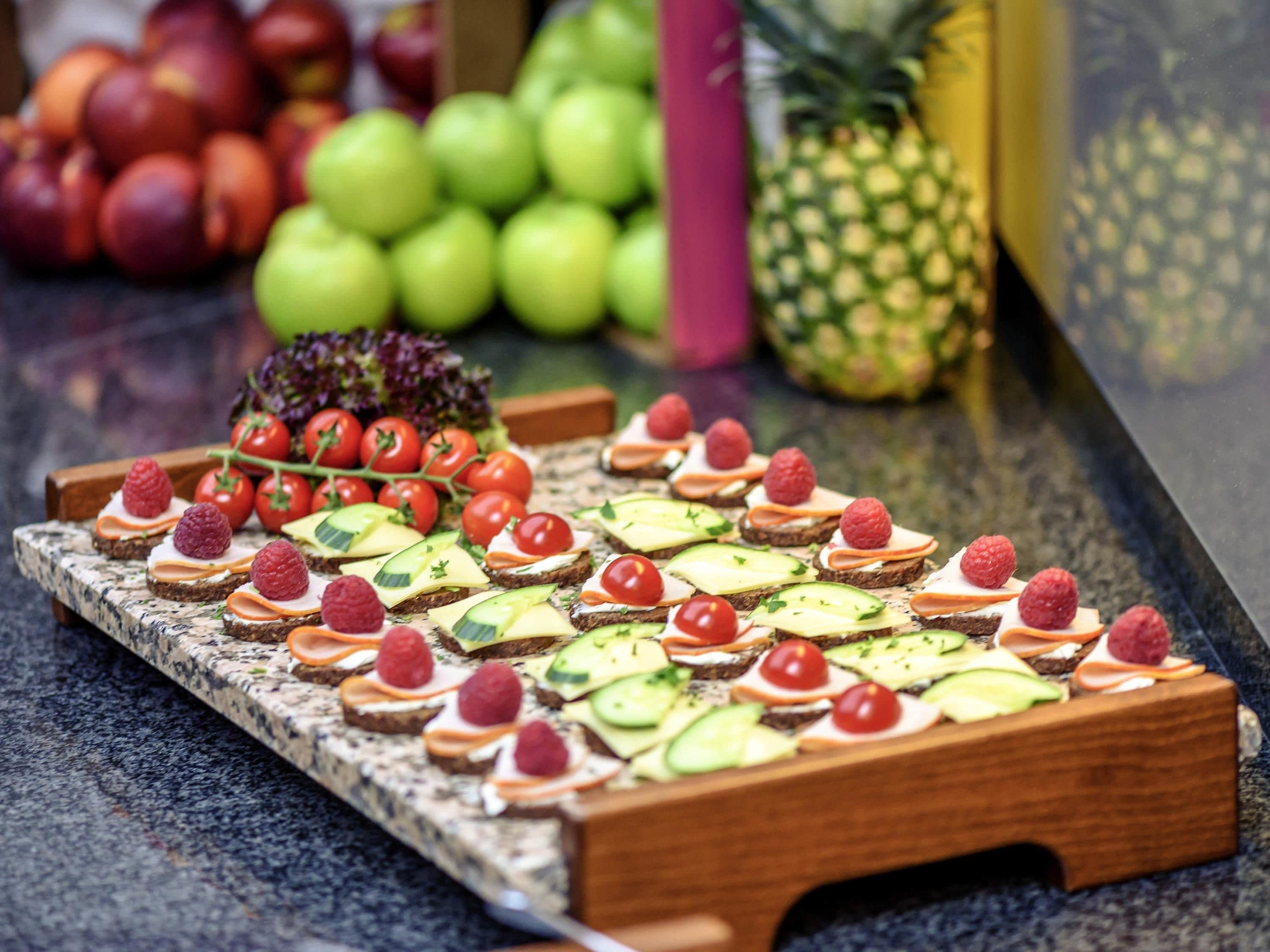 A wooden board with various fruit and cheese appetizers.