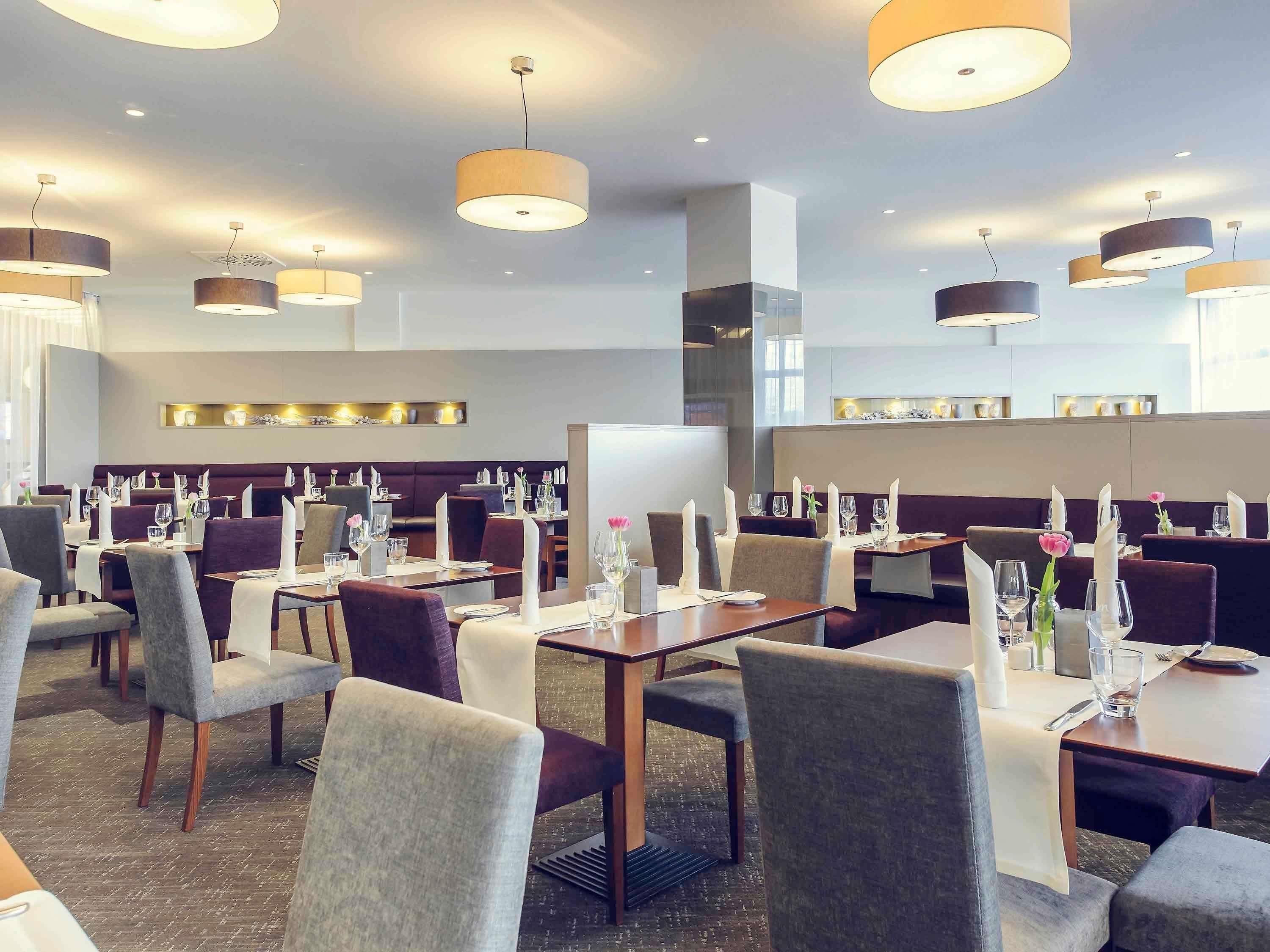 A restaurant with multiple tables, chairs, and pendant lighting.