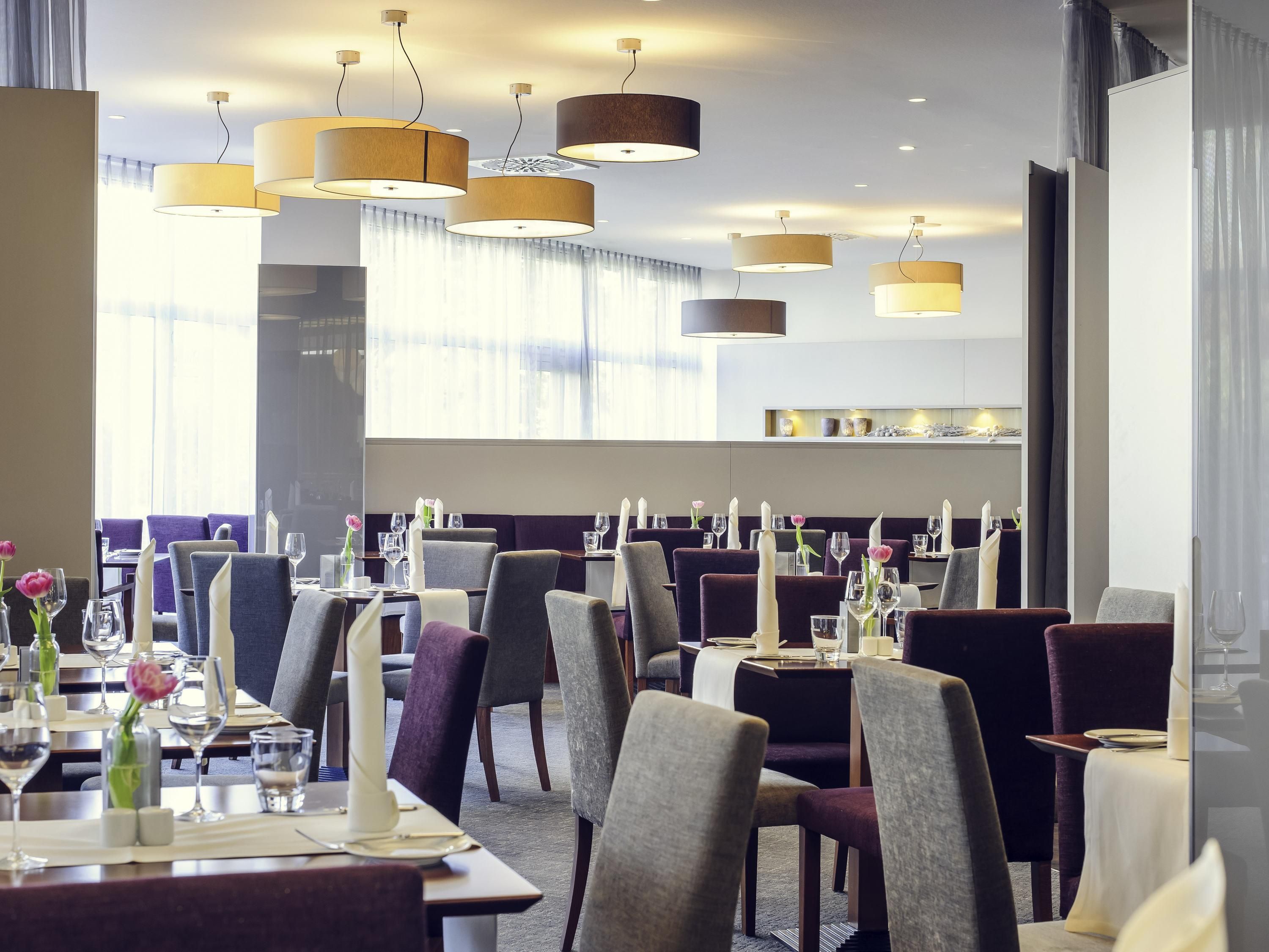 Un restaurant amb diverses taules, cadirees i llums penjants.