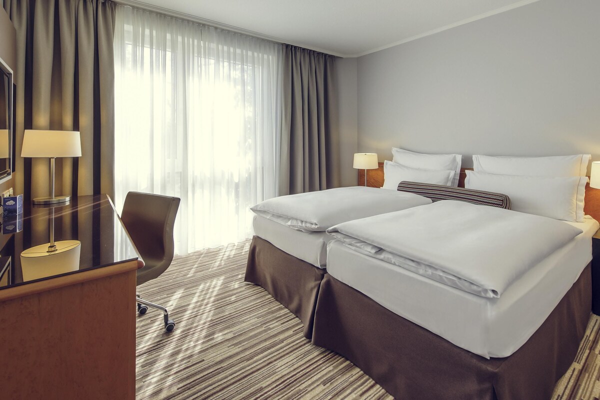 Une chambre d’h ôtel avec deux lits, un bureau, une chaise et un téléviseur.