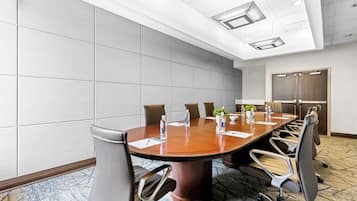 A conference room with a large oval table, six chairs, and a door in the background.