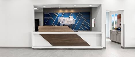 A reception area with a modern design, featuring a reception desk, a blue and white geometric wall, and a wooden accent.