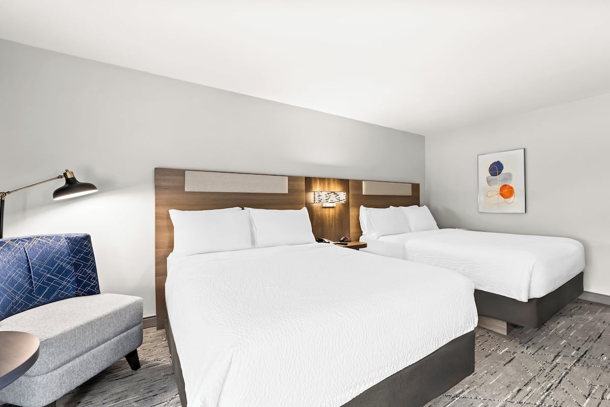 Une chambre d’hôtel avec deux lits, un bureau et une chaise.