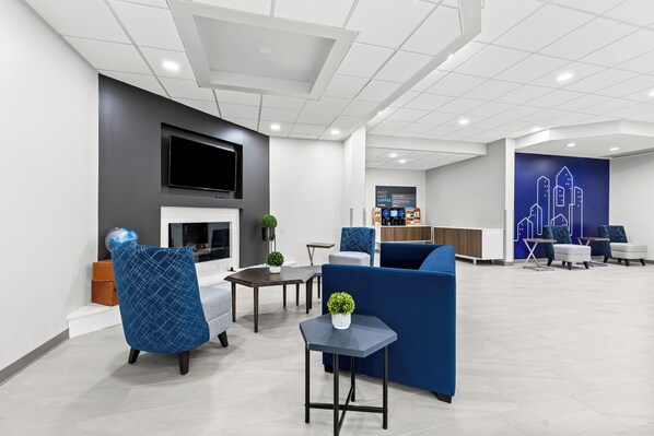 A modern lobby with seating areas, a fireplace, and a bar.