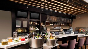 Un espace bar avec un tableau affichant le menu, des tabourets de bar et une variété de bouteilles et de verres.