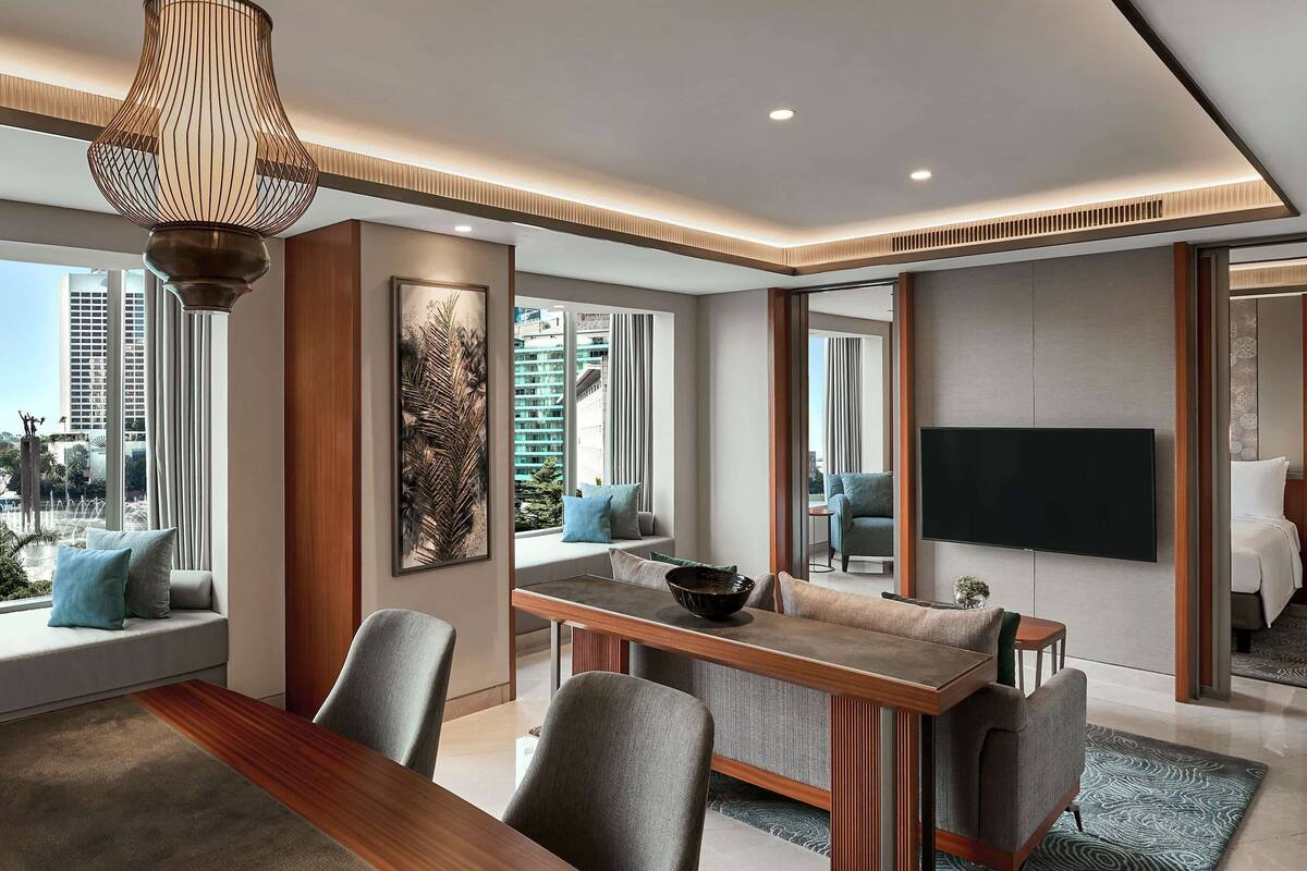 A modern living room with a dining area, large windows, and a flat-screen TV.