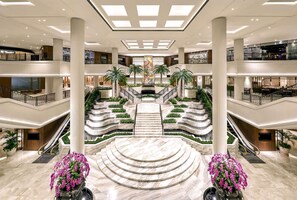 A multi-level atrium with marble flooring, palm trees, and a central staircase. - Grand Hyatt Jakarta (Jakarta)