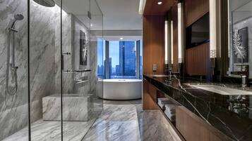 A modern bathroom with a glass-enclosed shower, a large bathtub, and a vanity with a black marble countertop.