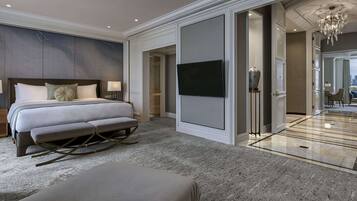 A modern hotel room with a large bed, a seating area, a television, and a bathroom with a glass door.