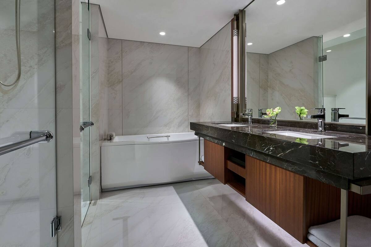 A modern bathroom with a glass-enclosed shower, a freestanding bathtub, and a vanity with a large mirror.