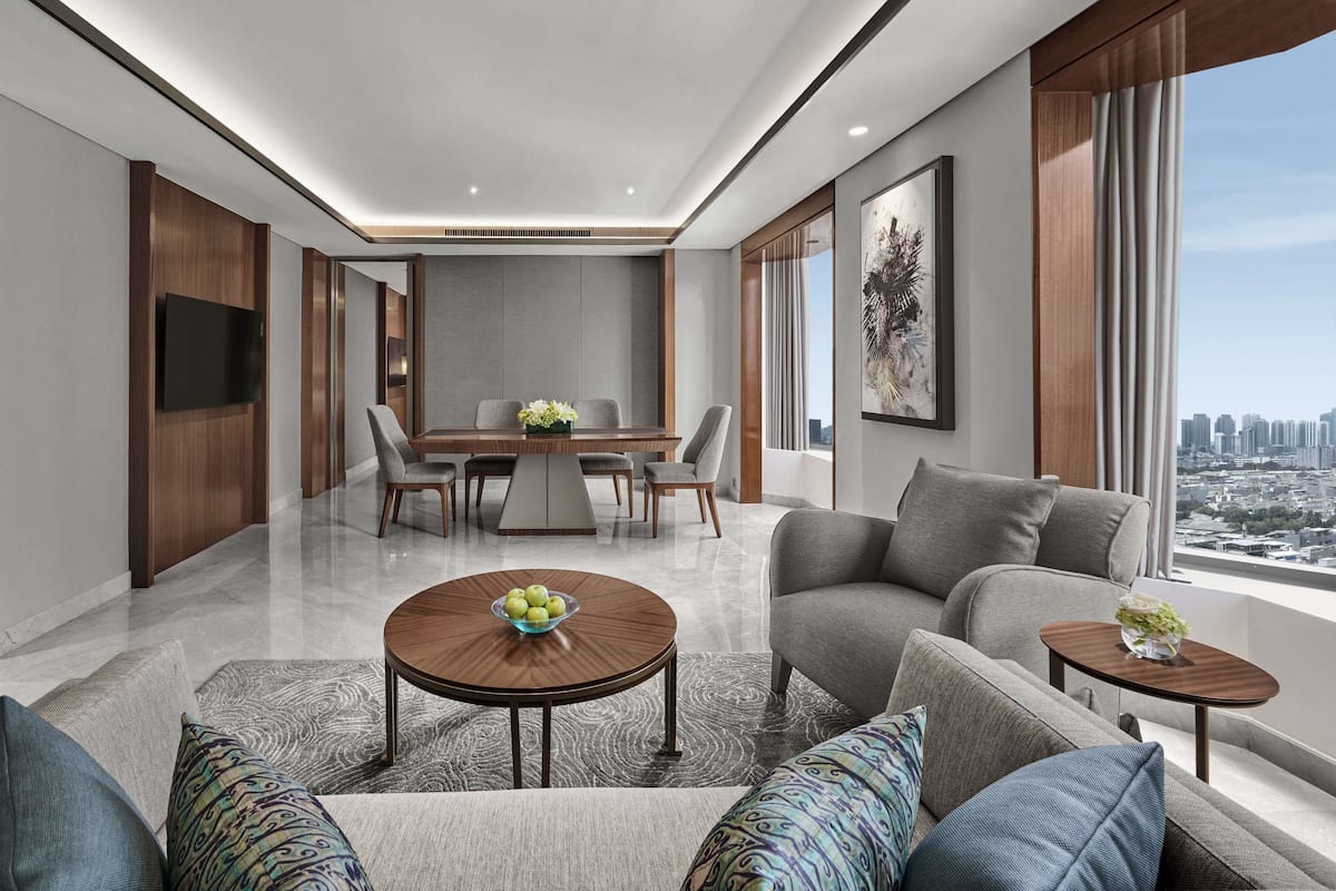 A modern living room with a dining area, large windows, and a city view.
