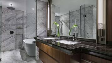 A modern bathroom with a marble floor, a freestanding bathtub, a large mirror, and a wooden vanity with two sinks.