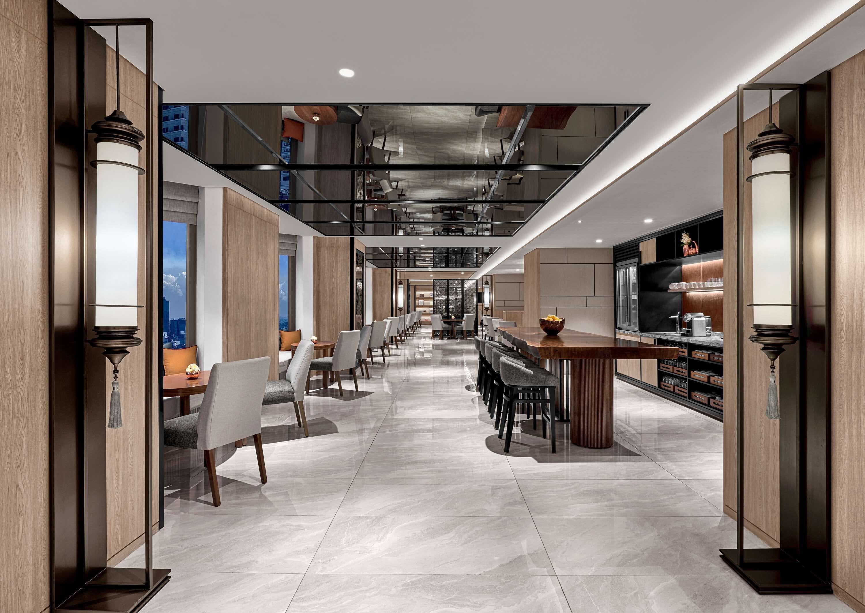 Eine moderne Hotelhalle mit einer langen Rezeption, einer Sitzgelegenheit und einer Bar.